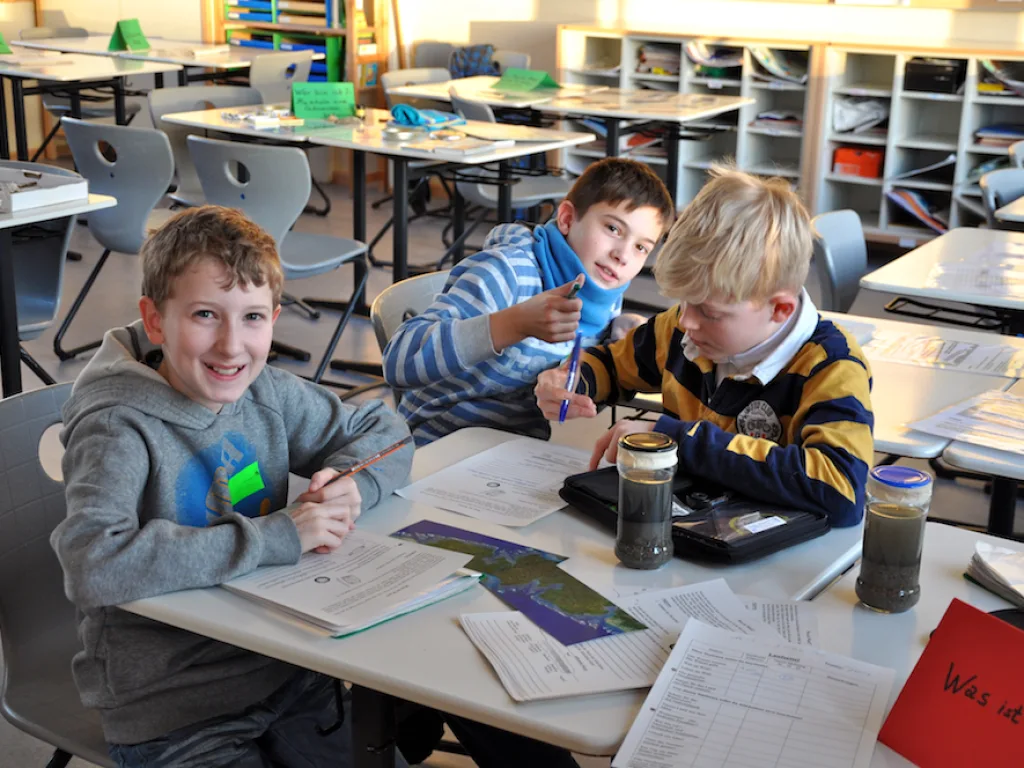 Kinder arbeiten an Tischen mit Gläsern und Material.
